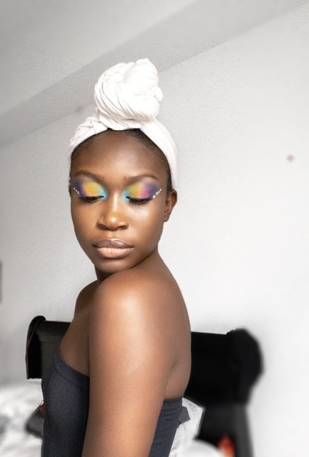 dark skin woman with fluffy brows and clear skin, showing how to create colourful eyeshadow.