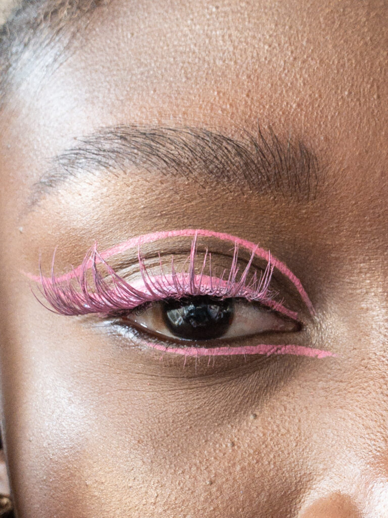 black woman applying pink graphic liner to eyelids
