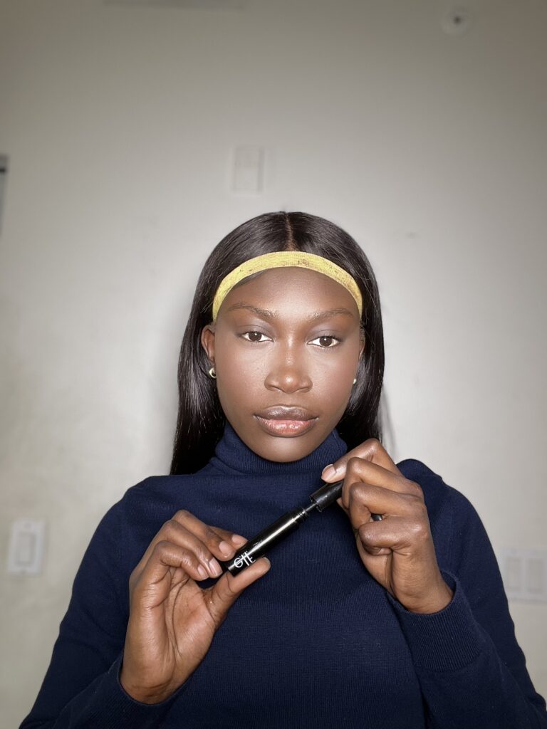 dark skin woman using elf volumizing mascara 