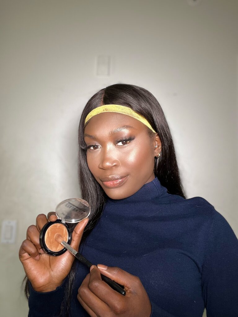 dark skin black woman using nyx hugh glass highlighter